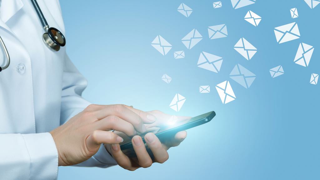 A person wearing a doctor's lab coat is using a smartphone. Icons of envelopes are floating away from the phone, symbolizing sending emails or messages. The background is a gradient of light blue.
